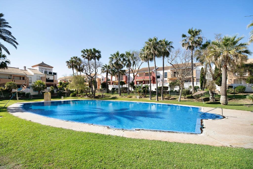 een groot blauw zwembad in een tuin met palmbomen bij leprince in Chiclana de la Frontera