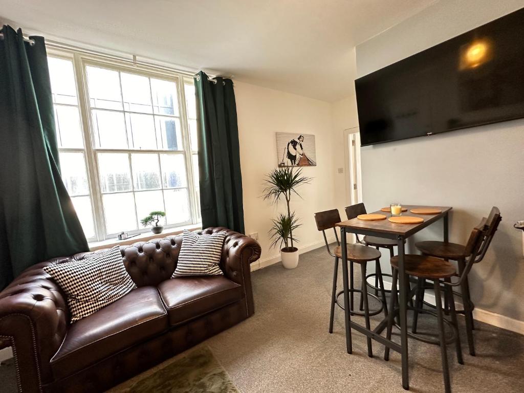 a living room with a leather couch and a table at Land Of Green Ginger Apartment- City Centre in Hull