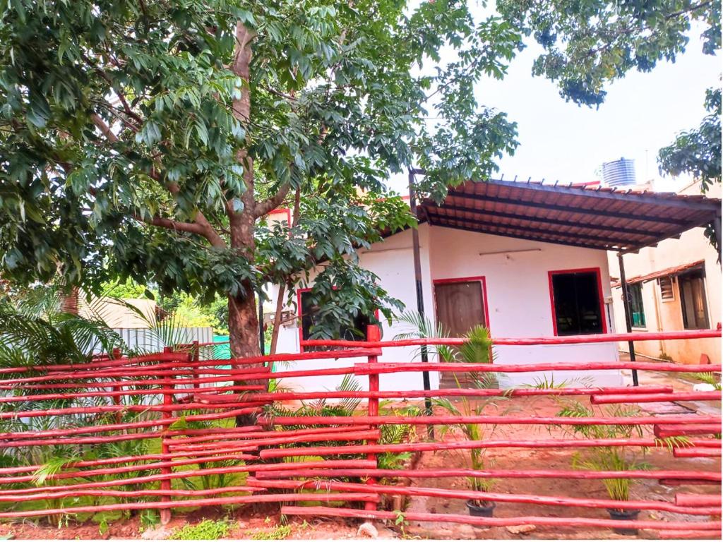 una cerca roja frente a una casa con un árbol en Golden Magnolia Homestay en Bangalore