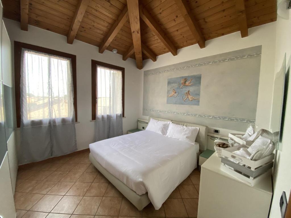 - une chambre avec un lit blanc et 2 fenêtres dans l'établissement Appartamento La Mansarda, à Cerea