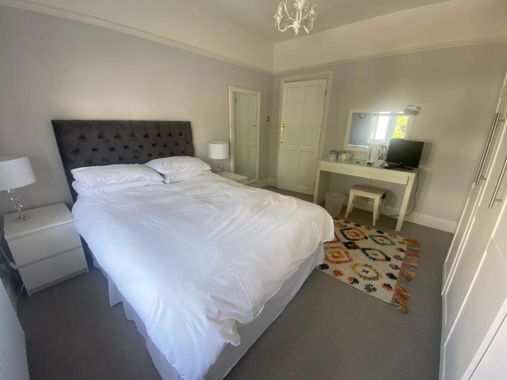 a bedroom with a large white bed and a desk at Rooms in Hadleigh,Essex in Hadleigh