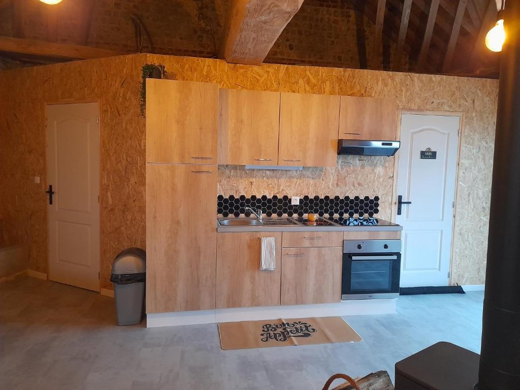 cocina con armarios de madera y horno con fogones en Le Manège, en Thiétreville