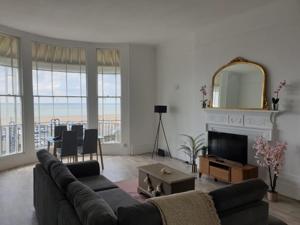 een woonkamer met een bank, een televisie en een tafel bij Period Sea view flat in Hastings in Hastings