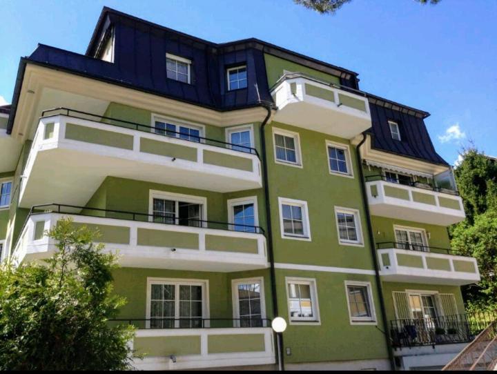 a large green and white building with a black roof at Green City Center Shared Apartment in Bad Ischl