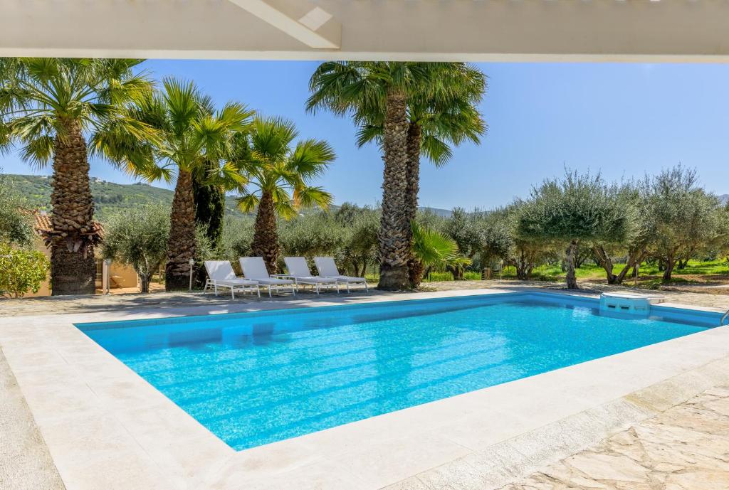 a swimming pool in a villa with palm trees at The Olive Grove Cottage with private swimming pool in Archanes