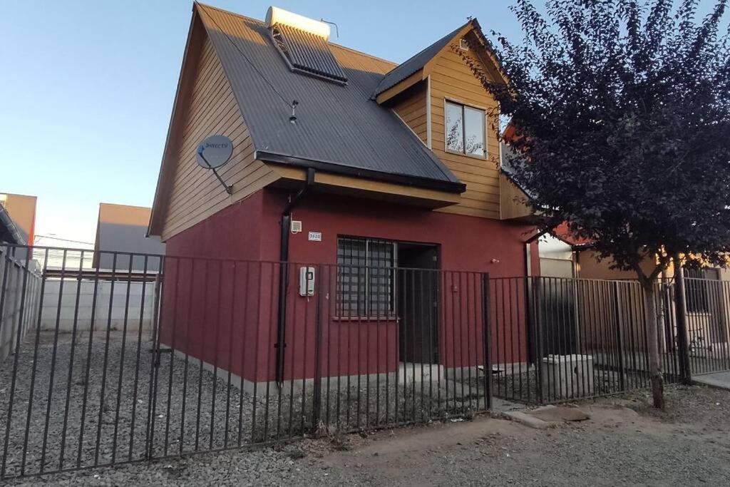 una casa roja con techo negro y valla en Cómoda casa en Talca, en Talca