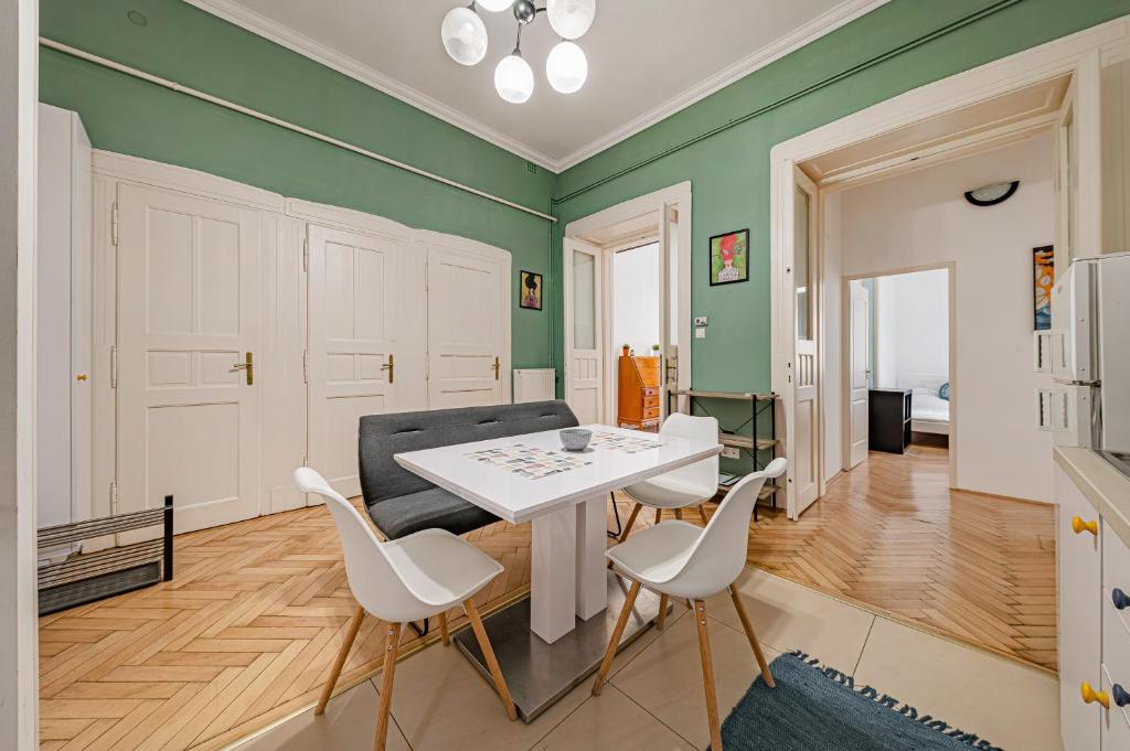 una sala de estar con paredes verdes y una mesa y sillas blancas. en Downtown Rooms Wesselenyi en Budapest