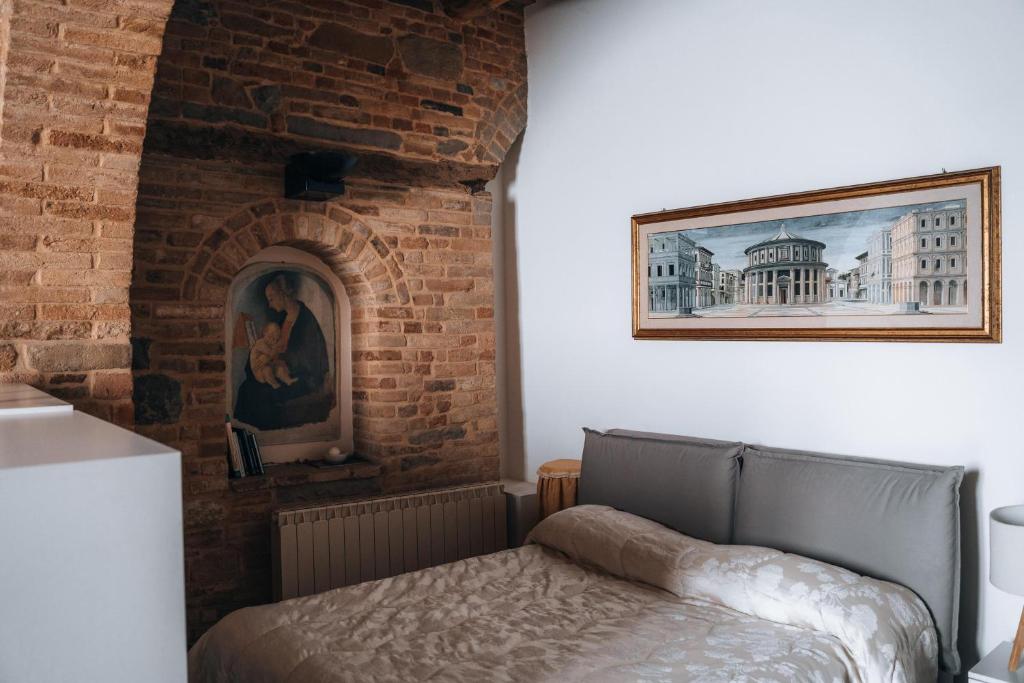 Cama en habitación con pared de ladrillo en Casa di Clara in Piazza, ideale per smartworking, en Amandola