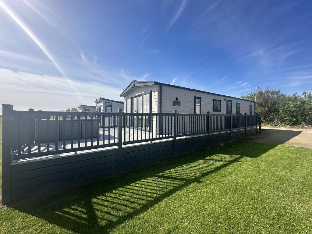 Luxury Lodge With Stunning Full Sea Views In Suffolk Ref 20234bs في Hopton on Sea: سور أسود في ساحة مع منزل