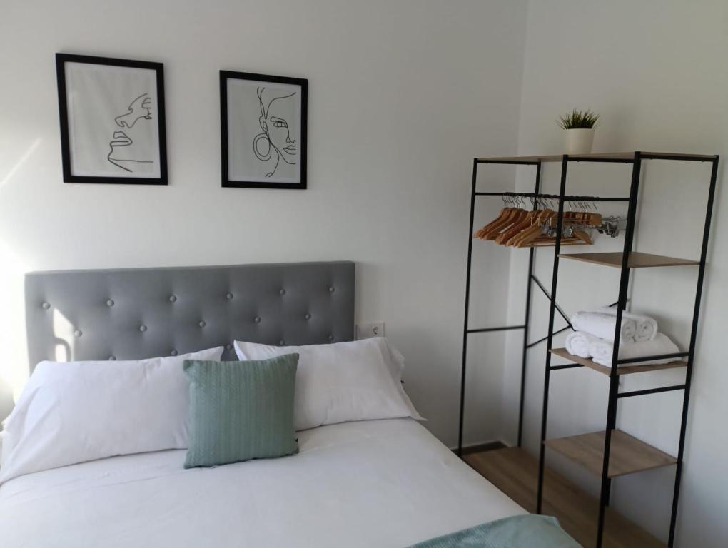 een slaapkamer met een wit bed met twee foto's aan de muur bij El Merendero in Utrera