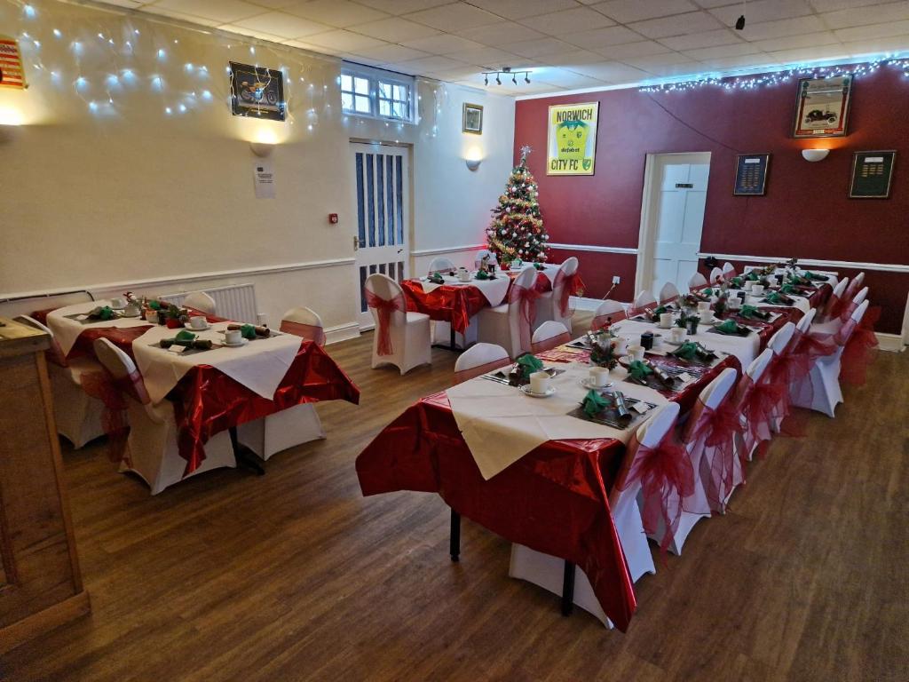 a banquet room with tables with red and white tablecloths at BJDS (dereham) ltd t/a kings head hotel in East Dereham
