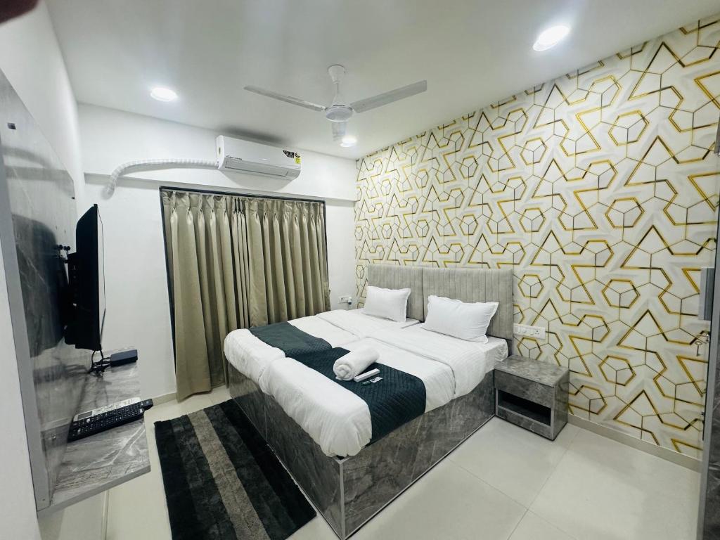 a bedroom with a bed and a tv and a wall at Astha Powai Service Apartment in Mumbai