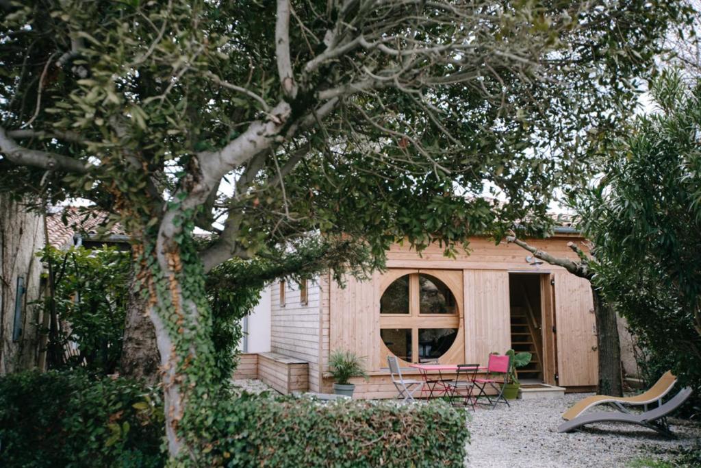 a house with two chairs and a table in a yard at Charming Tiny House in LʼIsle-sur-la-Sorgue
