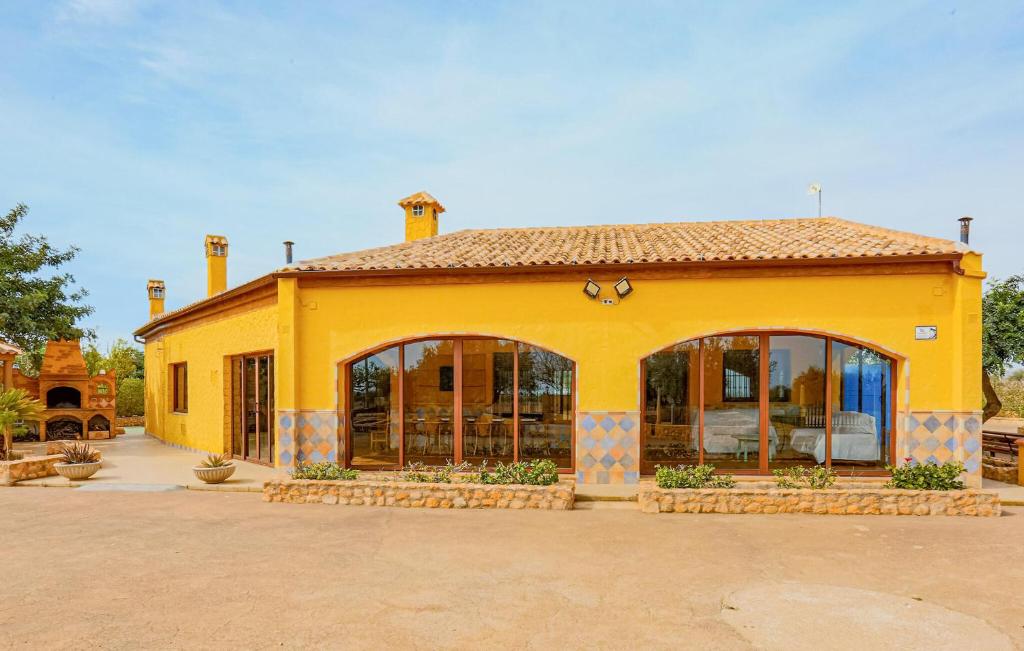 een geel gebouw met glazen deuren ervoor bij Lovely Home In Pozo De Los Palos With Kitchen 