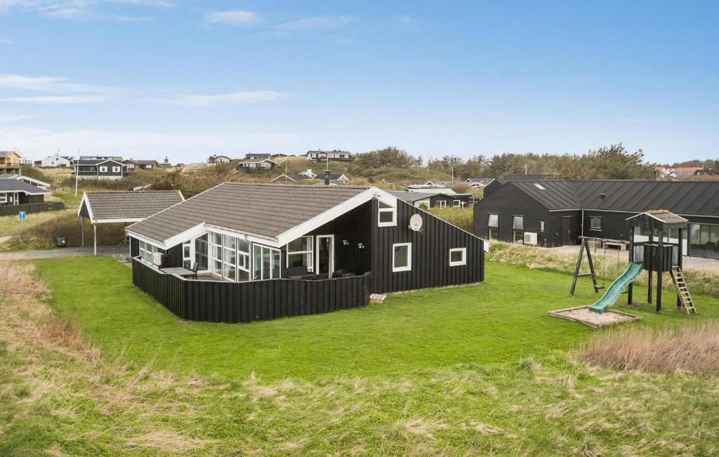 una casa negra con parque infantil y columpio en Amazing Home In Lkken With Sauna, en Løkken