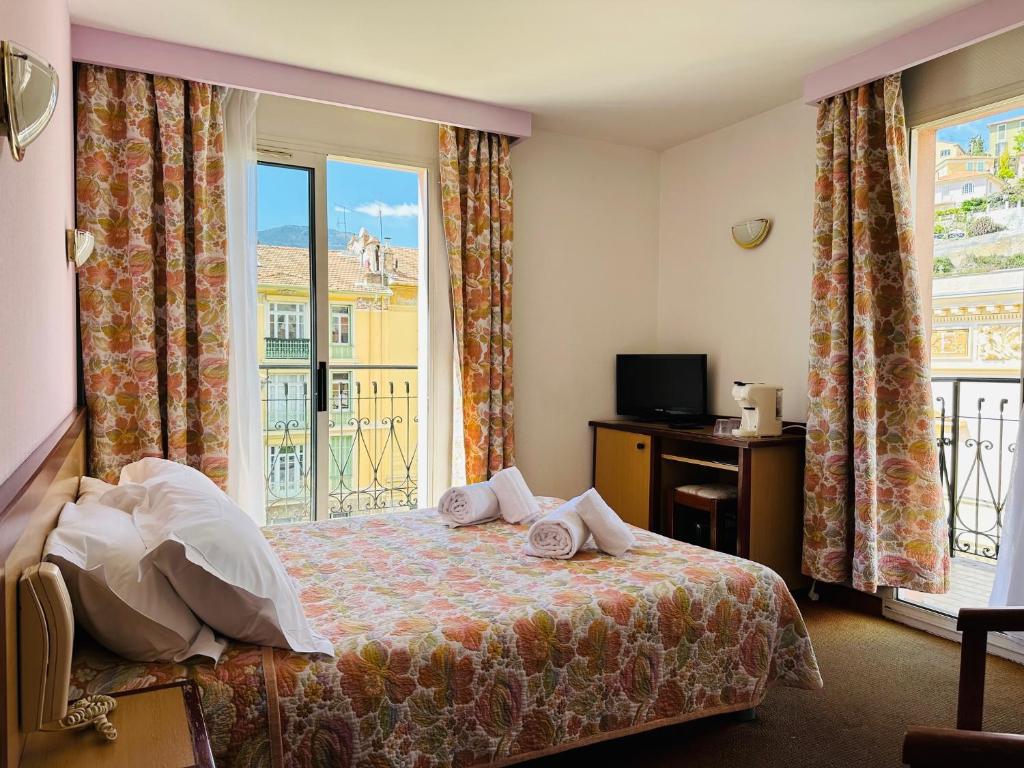 マントンにあるオテル Narev'sのベッドと窓が備わるホテルルーム