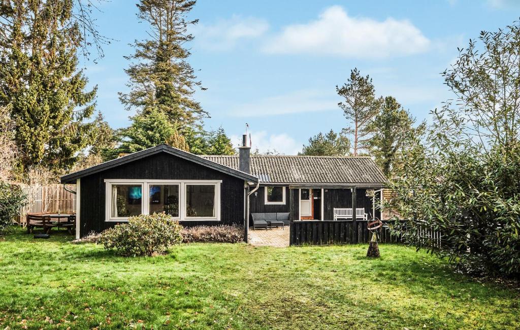 a black house in a yard with a grass field at Four-Bedroom Holiday Home In Vaggerlose in Marielyst