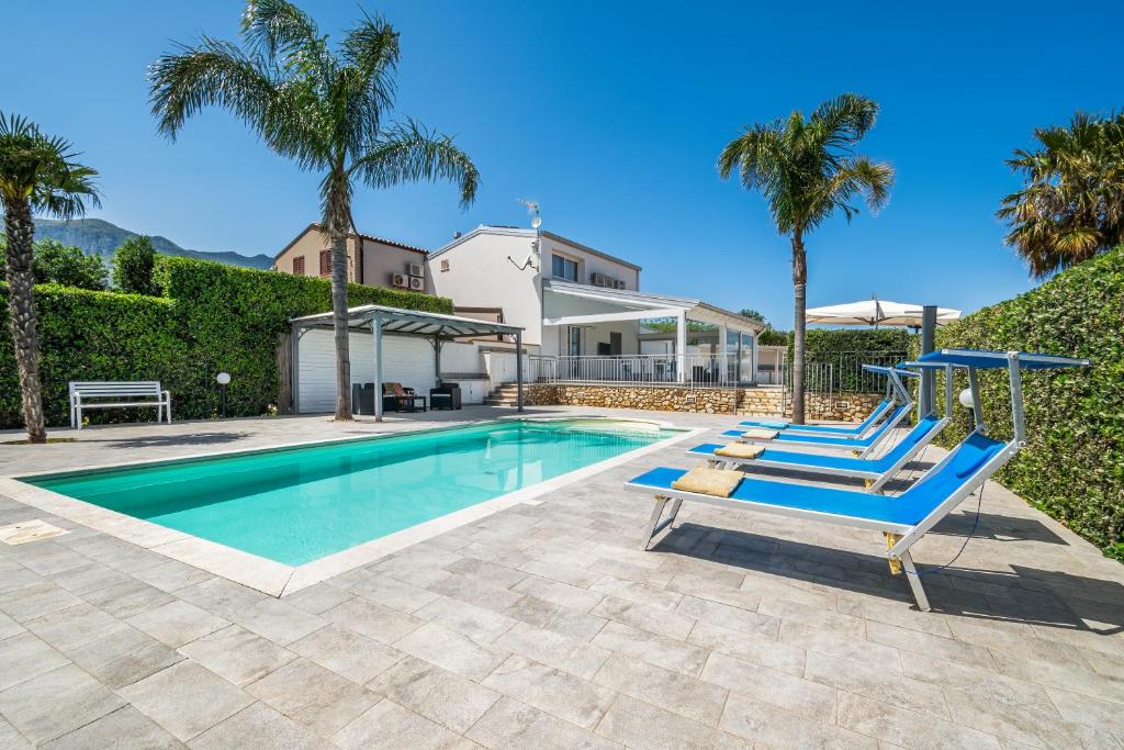 une piscine avec deux chaises longues et des palmiers dans l'établissement Villa DellUlivo, à Alcamo