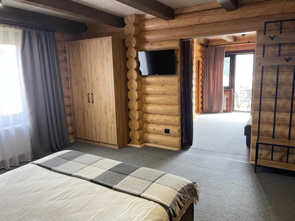 Schlafzimmer mit einem Bett und einem Flachbild-TV in der Unterkunft Вілла Розмарія in Jaremtsche