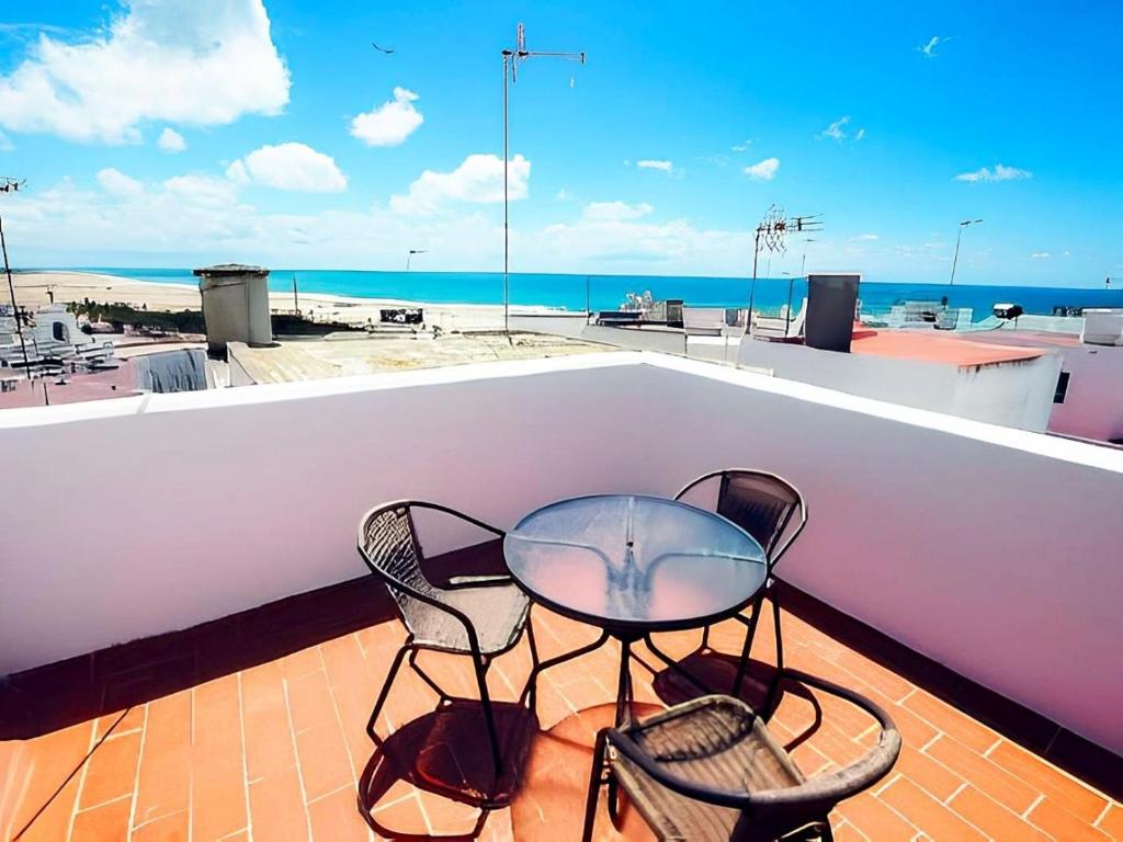 una mesa de cristal y 2 sillas en el techo en Apartamentos Cerca del Mar con Azotea Comunitaria, en Conil de la Frontera