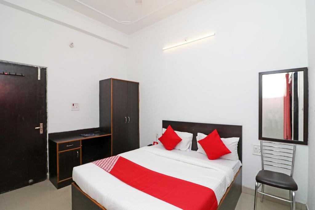 ein Schlafzimmer mit einem Bett mit roten Kissen und einem Stuhl in der Unterkunft OYO Flagship 24199 Hotel Mid Town Ojus Tower in Rudrapur