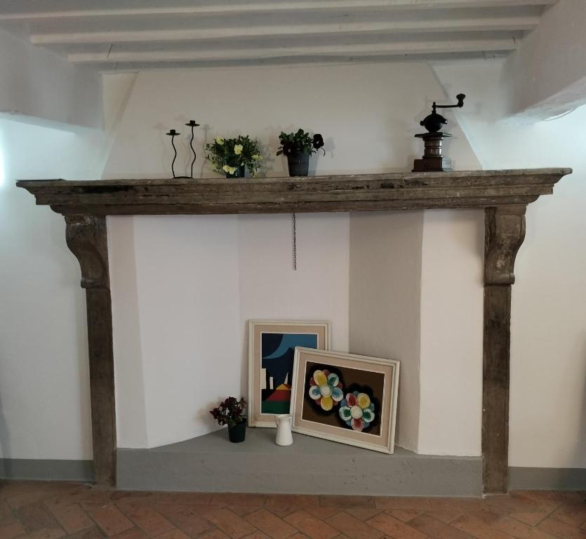 a fireplace with a wooden mantle with flowers on it at Palazzo Reali Apartment - Camera nella storia di Pistoia in Pistoia