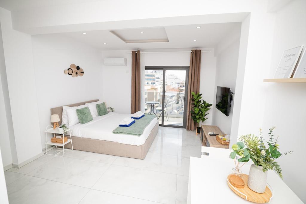 a white living room with a bed and a tv at Quattro City Center Ap 501B in Larnaka