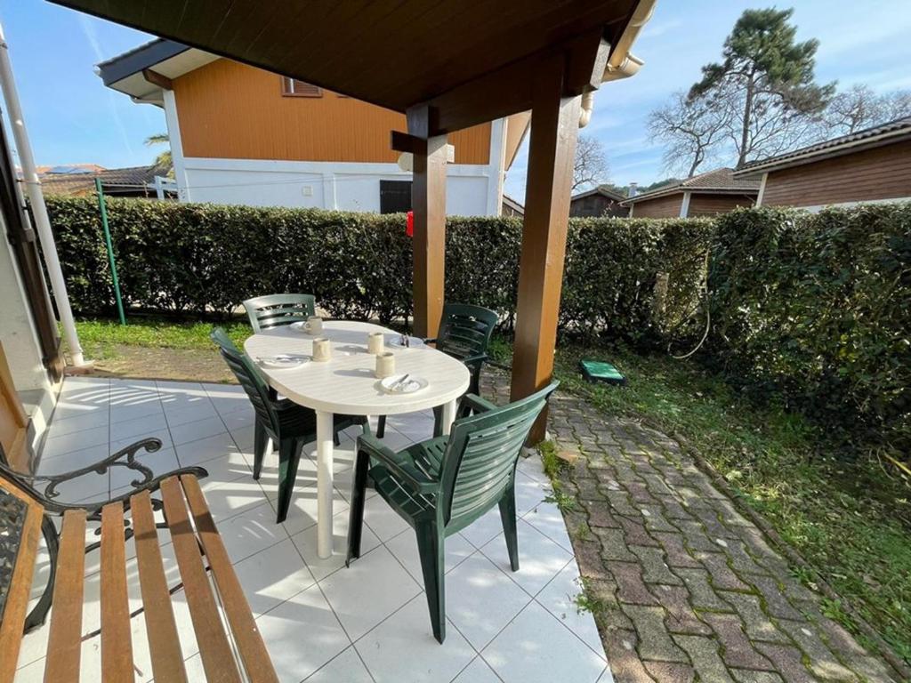 un patio avec une table et des chaises sur un patio dans l'établissement Maison calme avec piscine, 3 chambres, Capbreton - FR-1-413-114, à Capbreton