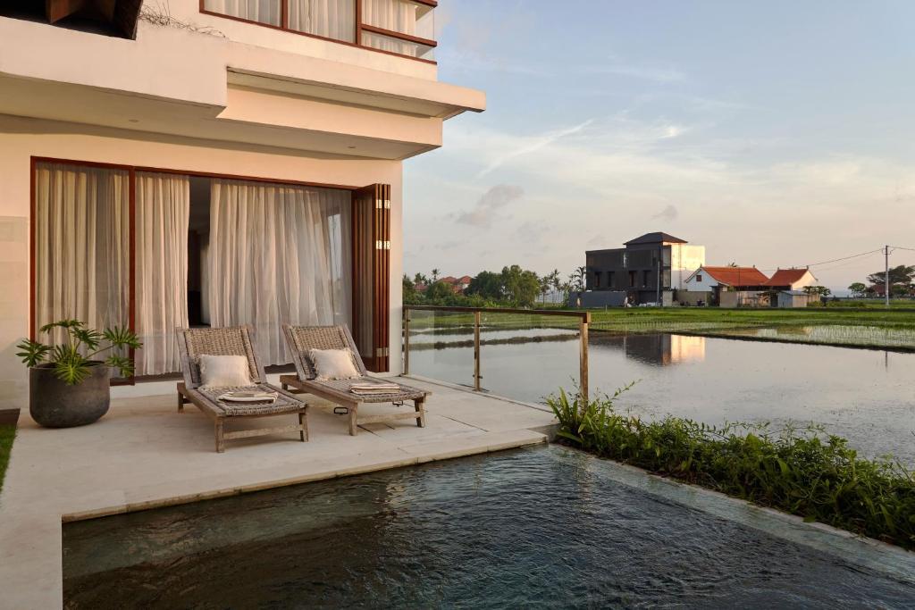 a house with two chairs and a swimming pool at Om Cemagi Beach Villa Canggu in Tanah Lot