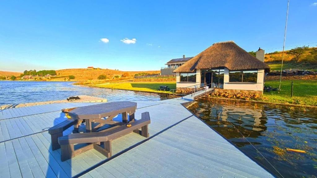 a wooden bench sitting on a dock next to a lake at LAKE-HOUSE CABIN in Witbank