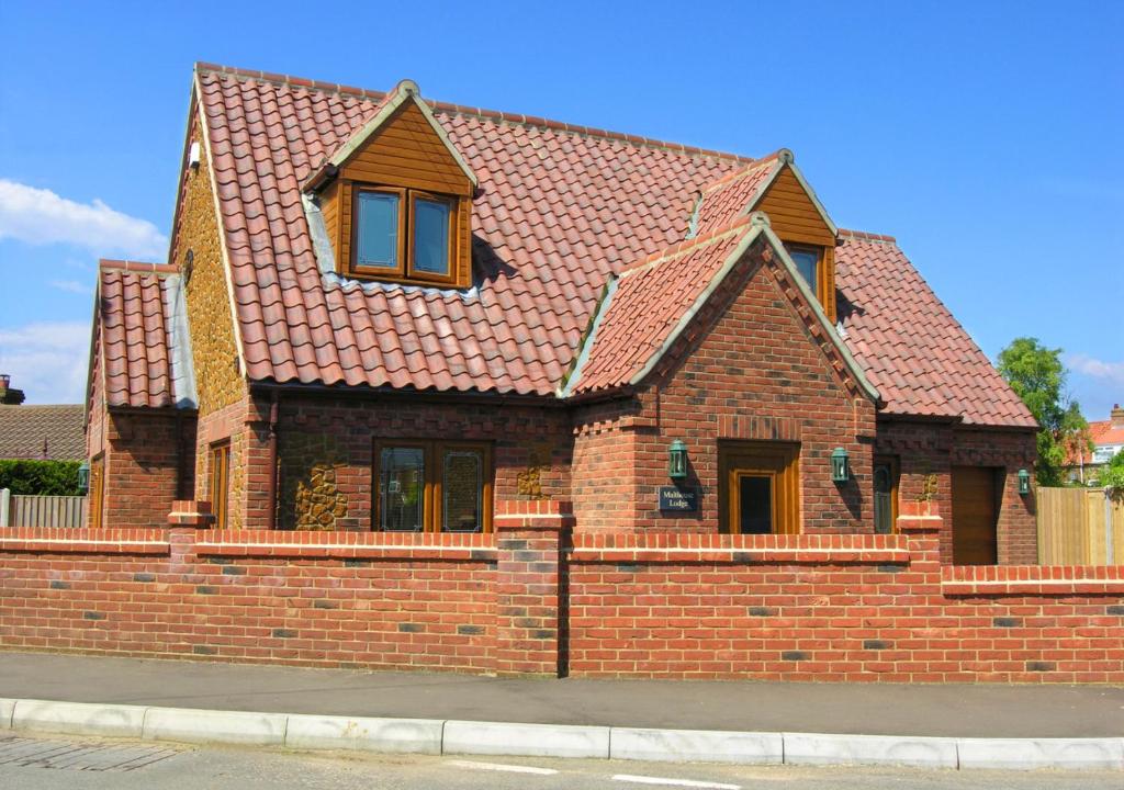 una casa de ladrillo con techo rojo en Malthouse Lodge en Heacham