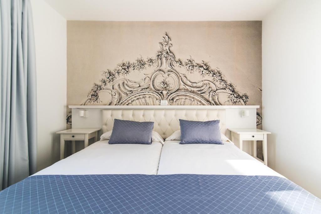 a bedroom with a large white bed with blue pillows at Mariposa Del Sol in Patalavaca