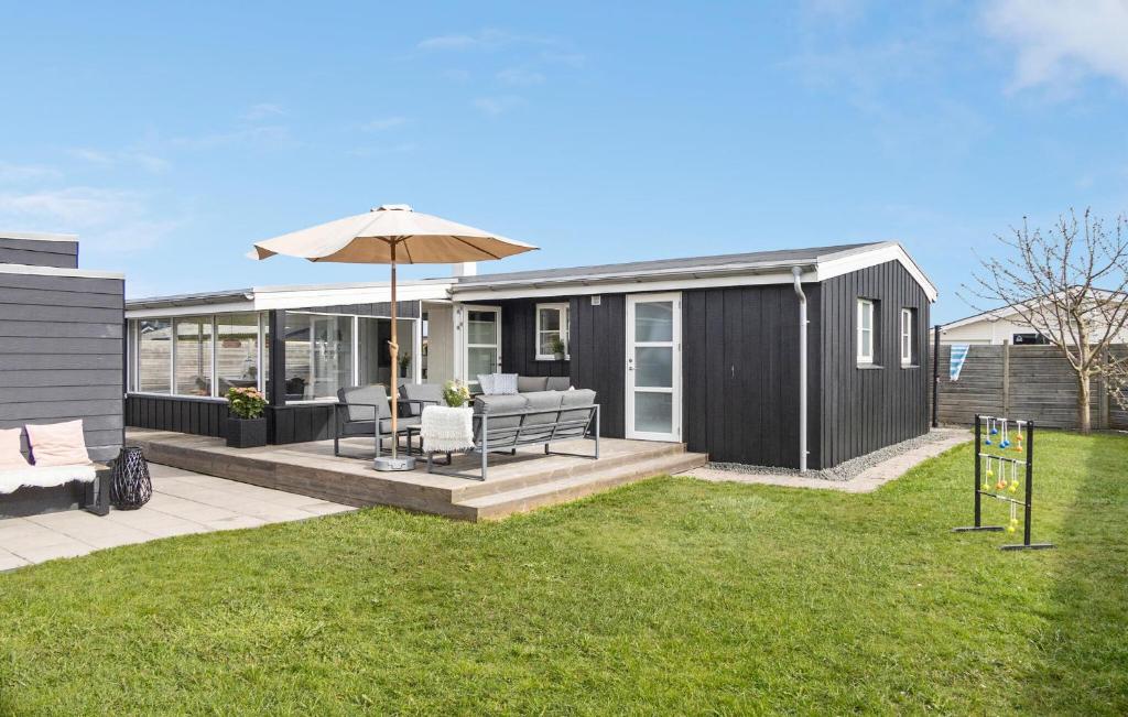 a black tiny house with a patio and an umbrella at Amazing Home In Otterup With Kitchen in Otterup