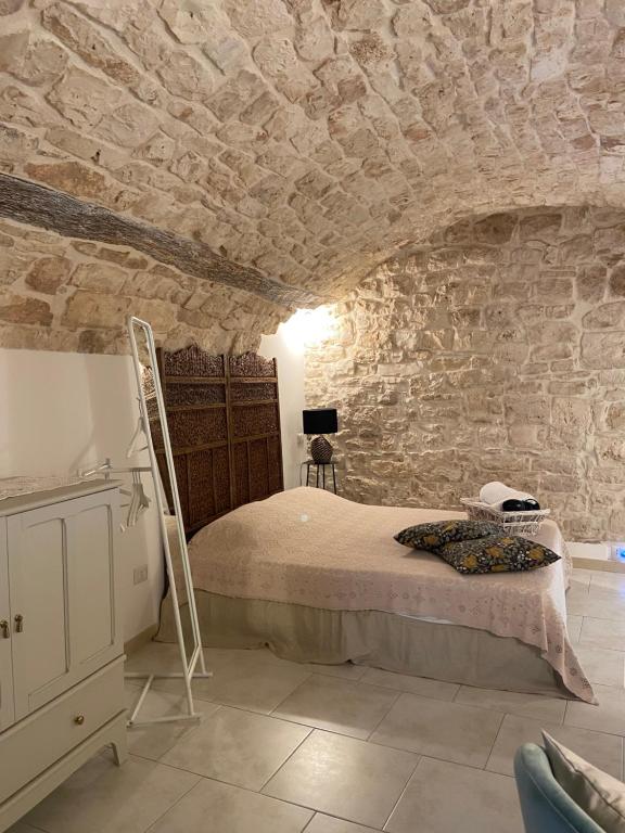 a bedroom with a bed and a stone wall at Le Badesse Mitrate by il pumo di puglia in Conversano