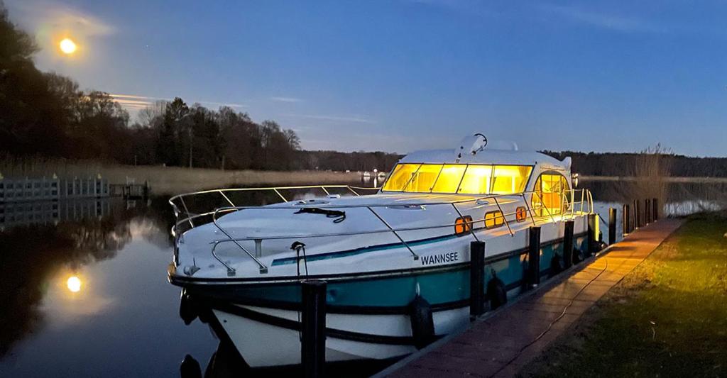 a boat is docked on the water at night at Kuhnle-Tours Hafendorf Müritz in Rechlin
