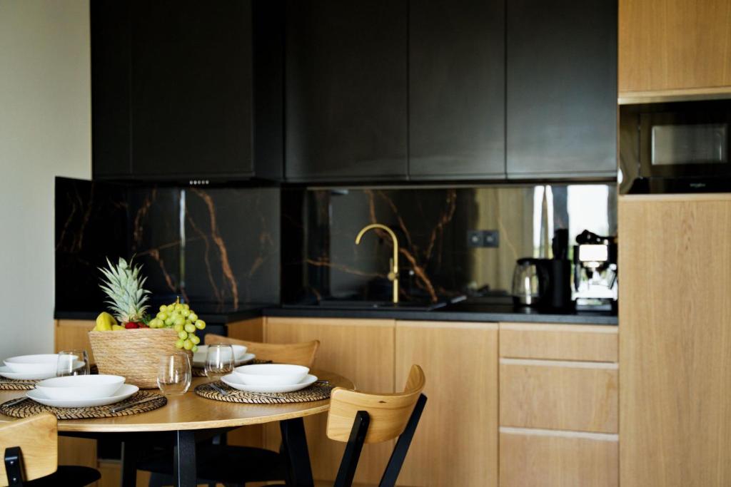 a kitchen with a table and chairs and black cabinets at Apartament Thaddeus 48 z tarasem in Zator