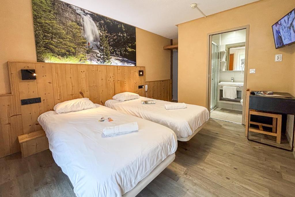 two beds in a hotel room with a tv at Domaine de Pyrène in Cauterets