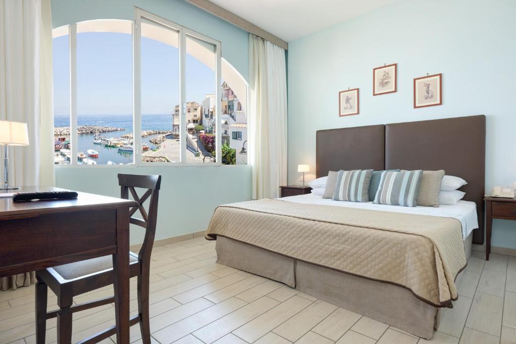 Schlafzimmer mit einem Bett, einem Schreibtisch und einem Fenster in der Unterkunft Sea Breeze Residence in Massa Lubrense
