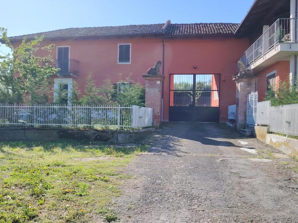 een rood huis met een poort en een oprit bij VILLA SAMUELA in Neive