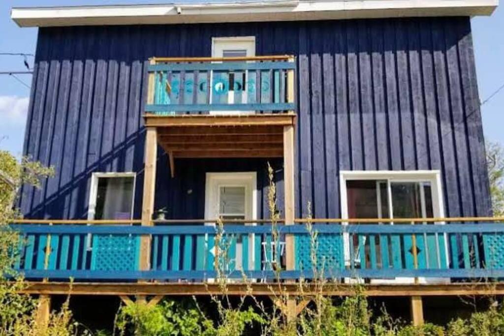 a blue house with a blue porch and a balcony at Loft La Coquille de Lune in Sainte-Rose-du-Nord
