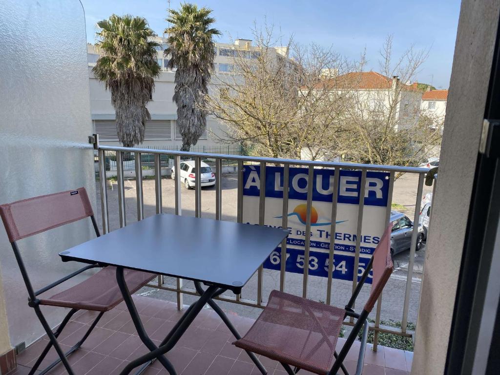 einen Tisch und Stühle auf einem Balkon mit einem Al-Pitcher-Schild in der Unterkunft Studio Balaruc-les-Bains, 1 pièce, 2 personnes - FR-1-553-41 in Balaruc-les-Bains
