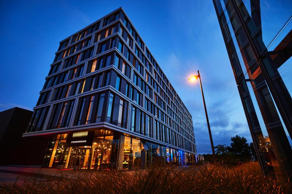 een hoog glazen gebouw met een straatlicht ervoor bij Steigenberger Hotel Bremen in Bremen