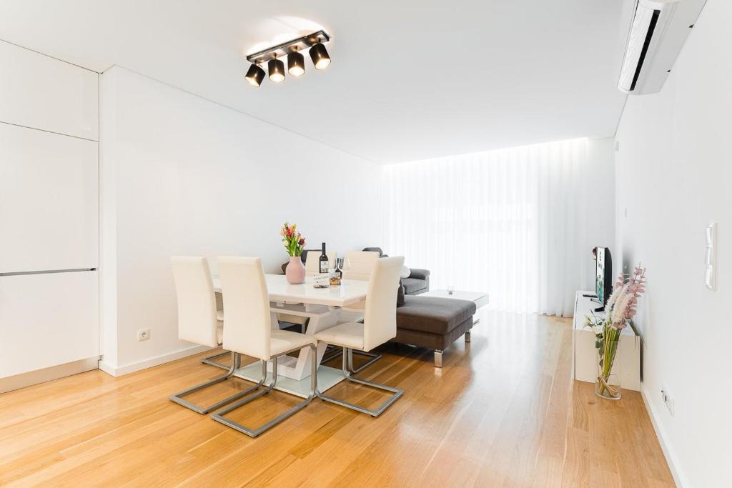 uma sala de jantar branca com uma mesa e cadeiras em GuestReady - Amazing Modern home near the beach em Vila Nova de Gaia