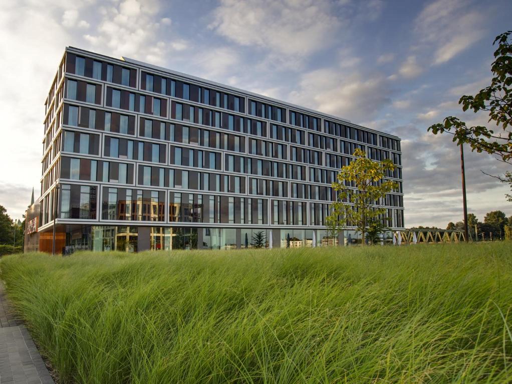 a tall building with a grass field in front of it at Steigenberger Hotel Bremen in Bremen