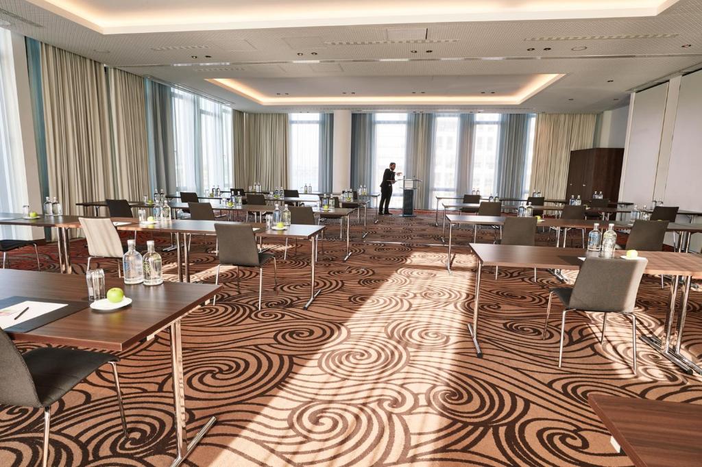 a room with tables and chairs and a person in the background at Steigenberger Hotel Bremen in Bremen