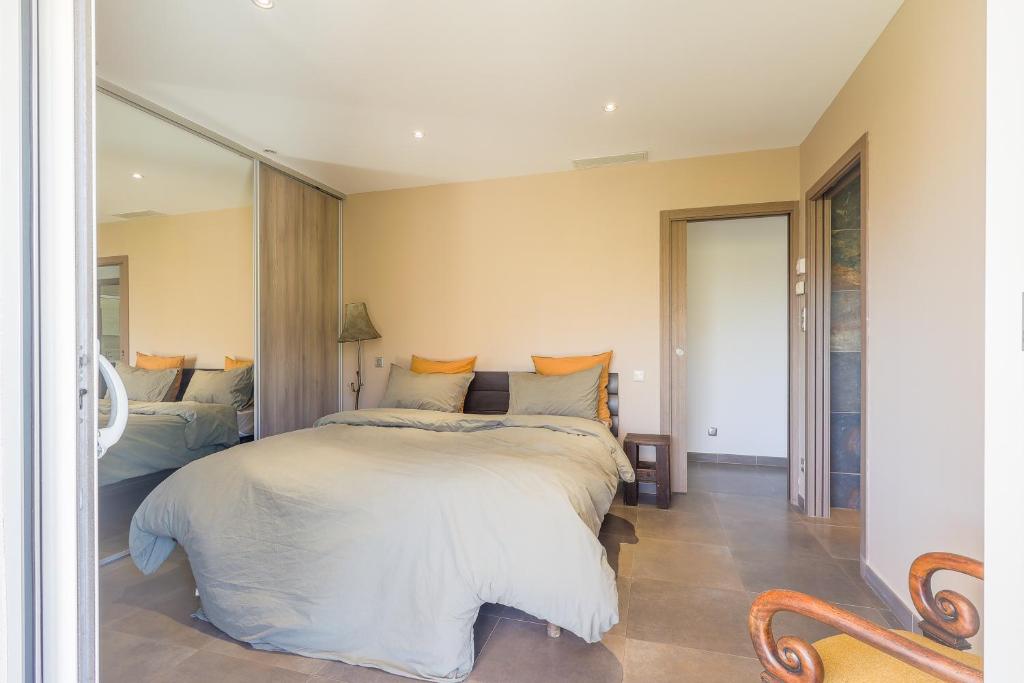 Un dormitorio con una cama y un espejo grande. en San Quilico - Maison climatisée piscine vue mer, en Aregno