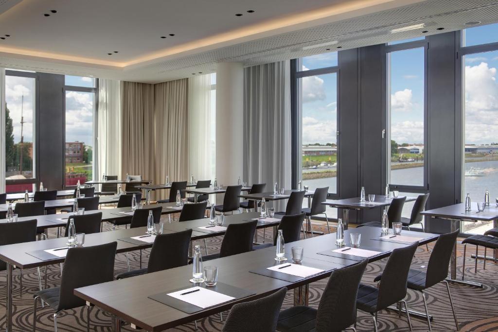 a row of tables and chairs in a room with windows at Steigenberger Hotel Bremen in Bremen
