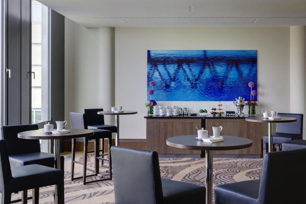 a restaurant with tables and chairs and a bar at Steigenberger Hotel Bremen in Bremen