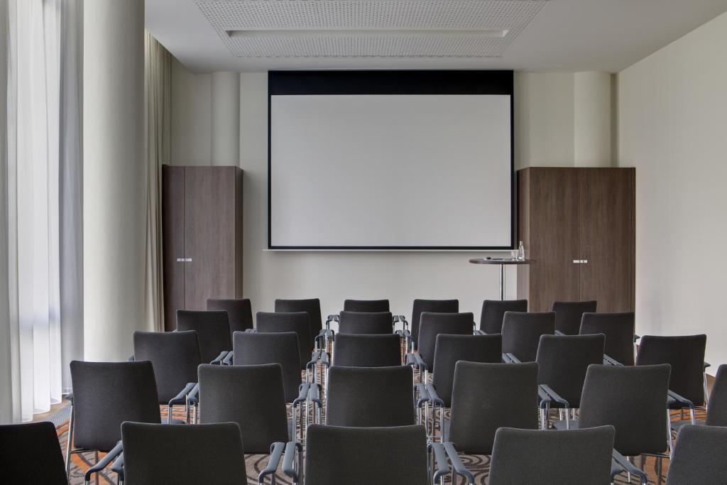 a conference room with chairs and a projection screen at Steigenberger Hotel Bremen in Bremen