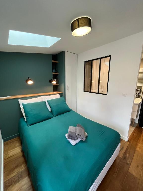 a bedroom with a green bed with a hat on it at Le bijou des carmes - Haut de gamme climatisé in Toulouse
